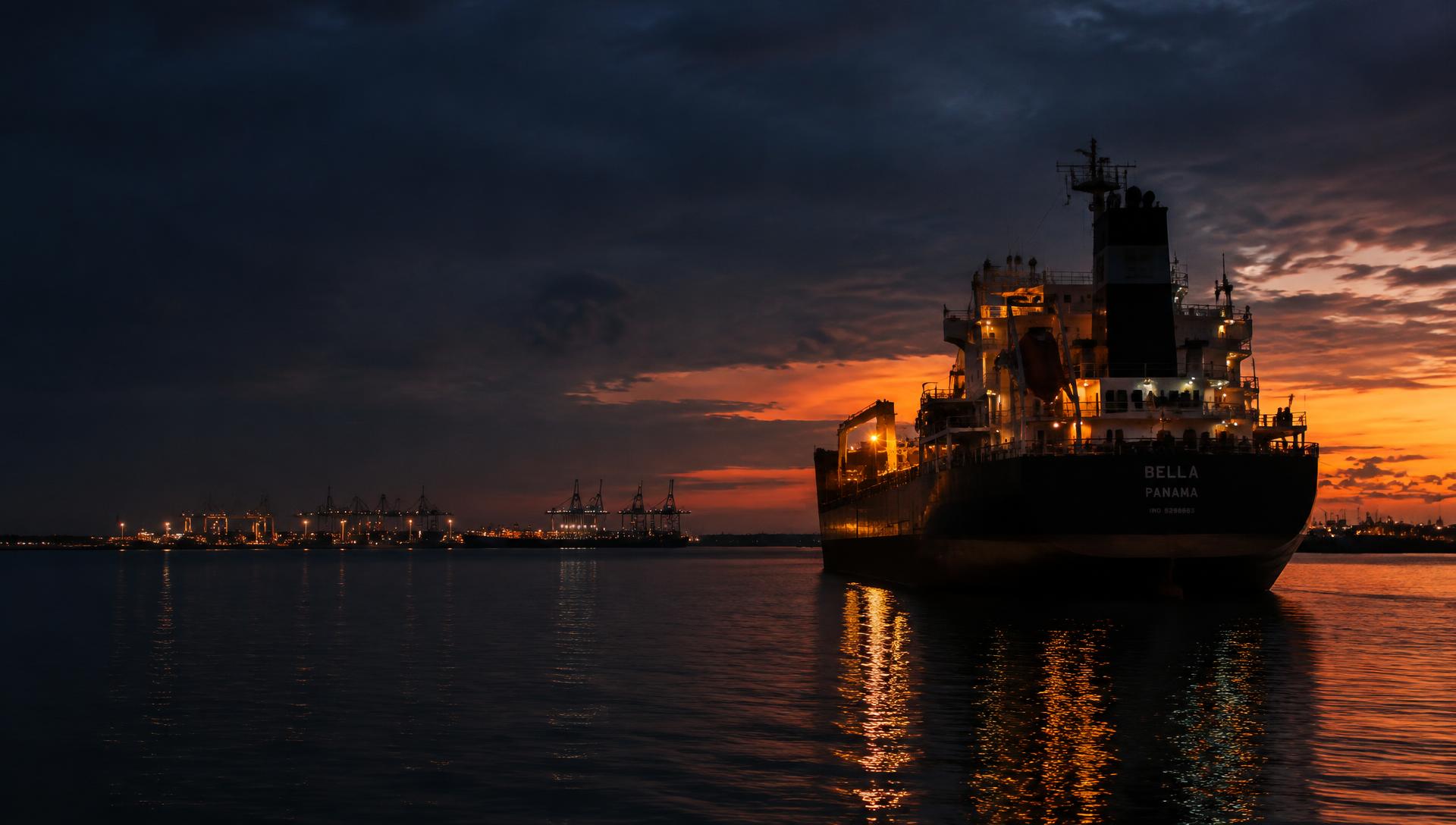 Cargo vessel at anchor near port at dusk